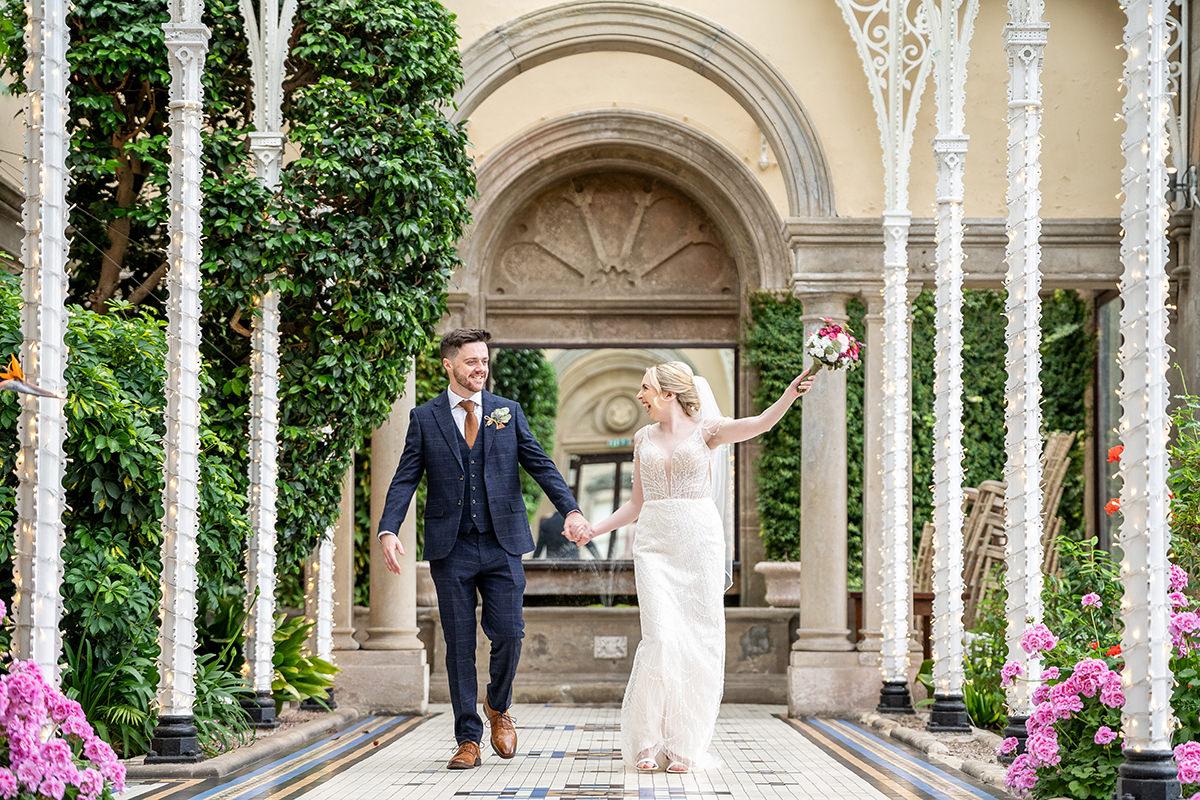 bride and groom walking looking at each other and laughing in Sandon Hall's Orangery